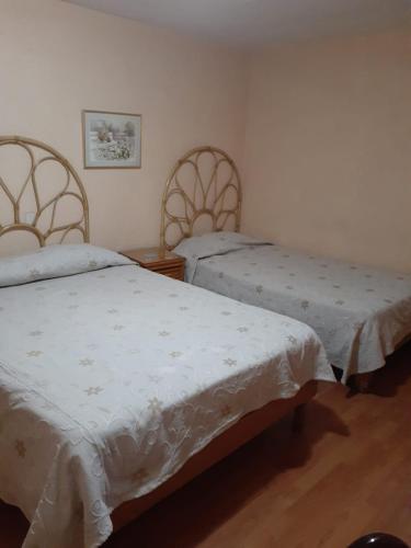a bedroom with two beds with white sheets on them at Hotel Canadá in Toluca