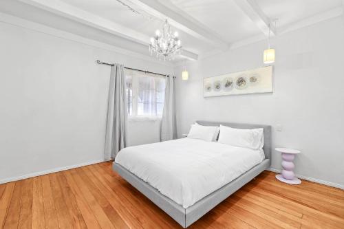 a white bedroom with a bed and a chandelier at Central Epsom Retreat in Auckland