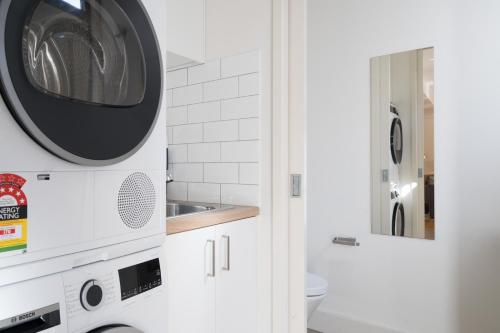 a white bathroom with a washer and dryer at StayCentral - Porte Prince in Melbourne