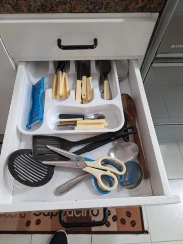 a drawer with scissors and other kitchen utensils at 50 m praia pitangueiras Guarujá espaço familiar in Guarujá