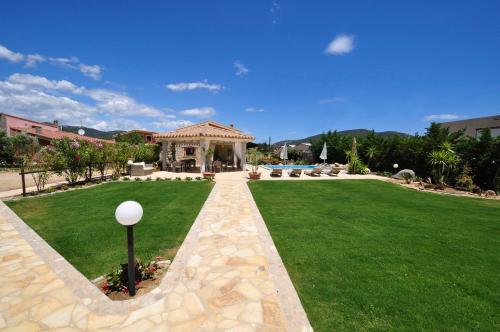 um jardim com um gazebo no meio de um relvado em Affittacamere B&B La Villa dei Graniti em Villasimius