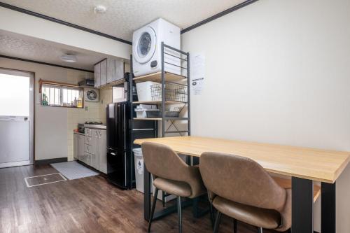 a kitchen with a table and chairs and a refrigerator at Atlantis 天下茶屋 in Osaka