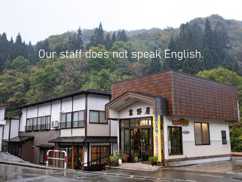 a building with a sign that reads our staff does not speak english at せせらぎの宿吉野屋 in Nishiwaga
