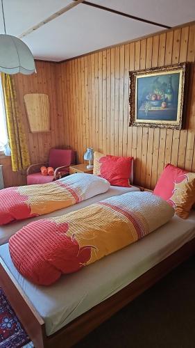 two beds in a room with wooden walls at Alphenrose saxeten in Saxeten