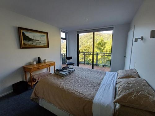a bedroom with a bed and a desk and a window at Moetapu Scenic Retreat in Linkwater