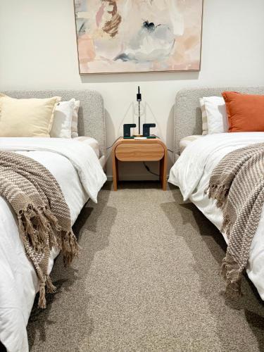 two beds in a room with a table between them at CBD Apartment, Sleeps 4 with Free Car Park in Melbourne