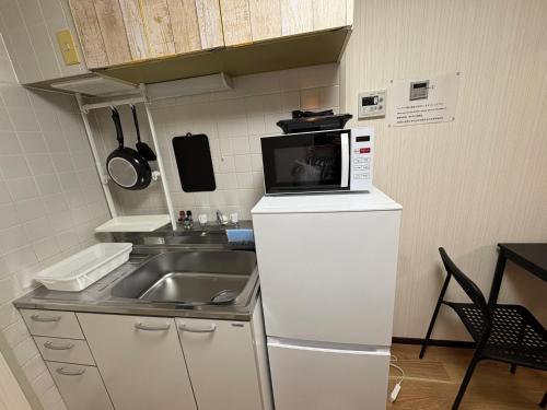 a kitchen with a microwave on top of a refrigerator at お宿あびこシルバーハイツ in Osaka