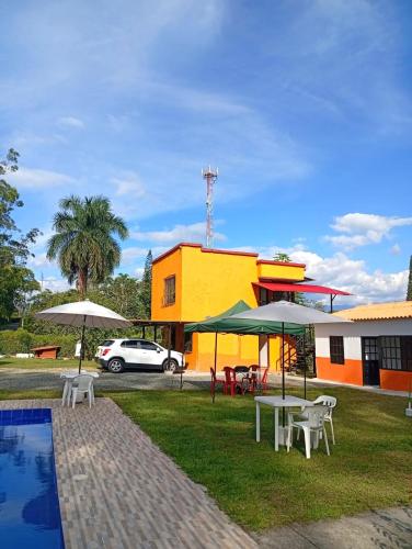 a patio with tables and umbrellas next to a building at FINCA Villa luna in Quimbaya