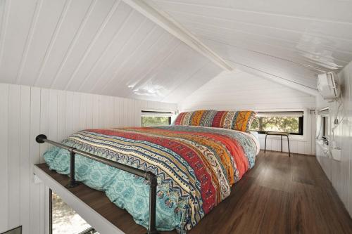a bed in the middle of a white room at Tiny Hideaway at Cloverhills by Tiny Away in Newham