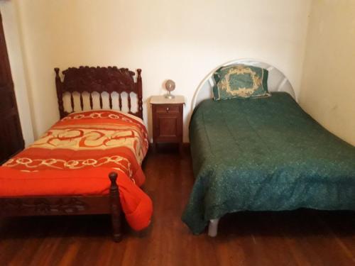 a bedroom with two beds and a table with a night stand at Departamento a 1 cuadra de la Plaza Principal in Sucre