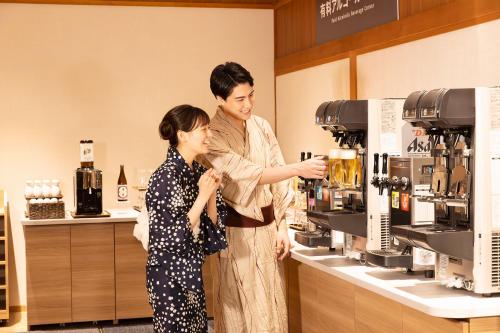 a man and a woman standing in a coffee shop at Ooedo Onsen Monogatari Premium SendaiSakunami in Sendai