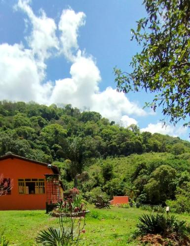 an orange house on a green hill with trees at Casa de campo 2qtos região de Extrema in Extrema