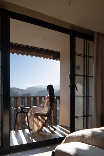 a woman sitting in a chair on a balcony at Seven Letters · Zhanyue Hotel in Xijiang