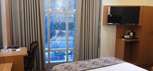 a room with a window and a bed and a television at Shine Hospitality Premium in Mumbai