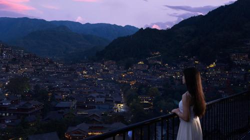 a woman standing on a balcony looking at a city at Seven Letters · Zhanyue Hotel in Xijiang
