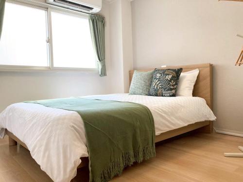 a bedroom with a large bed with a window at Liaison Apartment Shinsaibashi in Osaka
