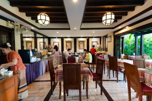 a restaurant with people sitting at tables and a counter at Viang Thapae Resort in Chiang Mai