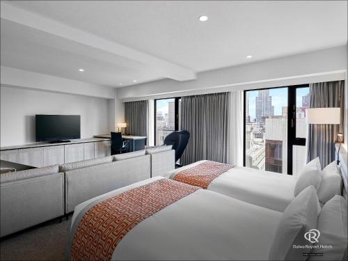 a hotel room with two beds and a television at Daiwa Roynet Hotel Sendai Ichibancho PREMIER in Sendai