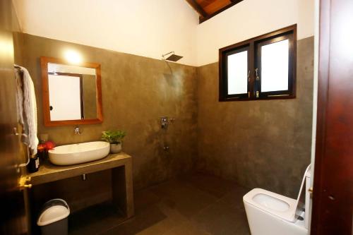 a bathroom with a sink and a toilet and a mirror at Hiriketiya Nanda Homestay in Dickwella