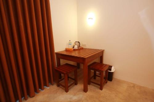 a wooden table with two stools next to a curtain at Hiriketiya Nanda Homestay in Dickwella