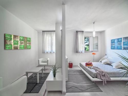 a white bedroom with a bed and a chair at Tranquil Escape in Tavullia in Tavullia