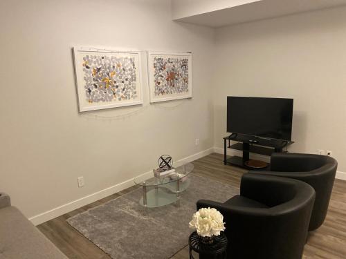 a living room with two chairs and a flat screen tv at Brand new suite with parking pad at the back in Calgary