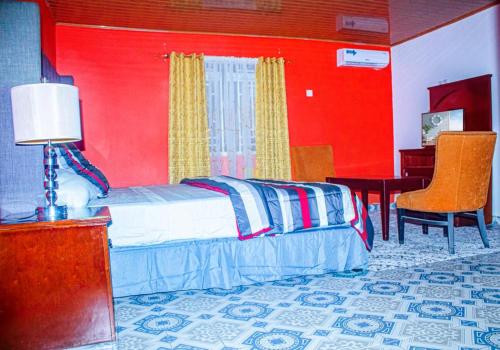 a bedroom with red walls and a bed with a desk at Elevation Lodge Imatt in Freetown