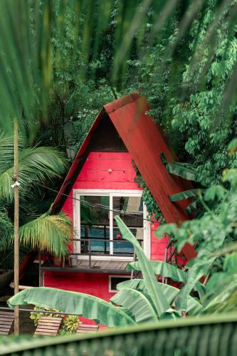 a red house with a window in the forest at Greengos Hotel in Lanquín