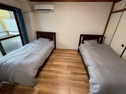 two beds sitting next to each other in a room at お宿あびこシルバーハイツ in Osaka