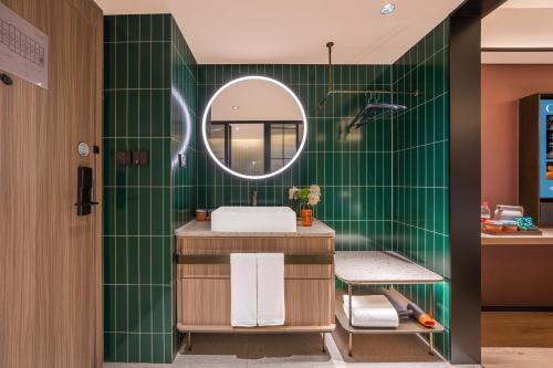 a green tiled bathroom with a sink and a mirror at Orange Hotel Beijing Xi'erqi in Beijing