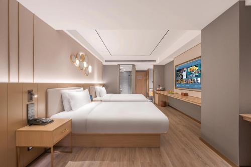 a bedroom with a large bed and a tv at Orange Hotel Beijing Xi'erqi in Beijing