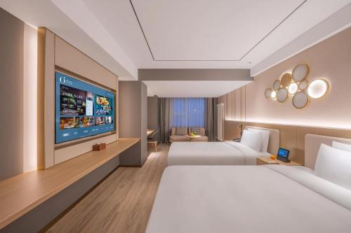 a hotel room with two beds and a flat screen tv at Orange Hotel Beijing Xi'erqi in Beijing
