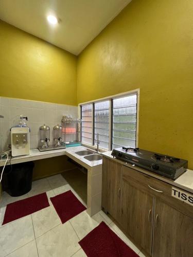 a kitchen with yellow walls and a sink and a window at Mahsuri Dorm, Roomstay & Homestay Langkawi in Ulu Melaka