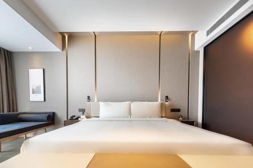 a bedroom with a large bed and a blue couch at Atour Hotel Shunde Midea Yueran Plaza Foshan in Shunde
