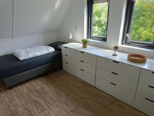 Un dormitorio con una cama, una cómoda y ventanas. en Bungalow in Breskens near the Coast, en Breskens