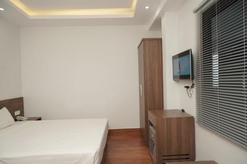 a bedroom with a bed and a flat screen tv at Cam Ranh Surf Home in Cam Lâm
