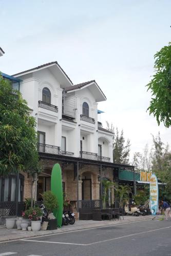 a white building with a surfboard in front of it at Cam Ranh Surf Home in Cam Lâm
