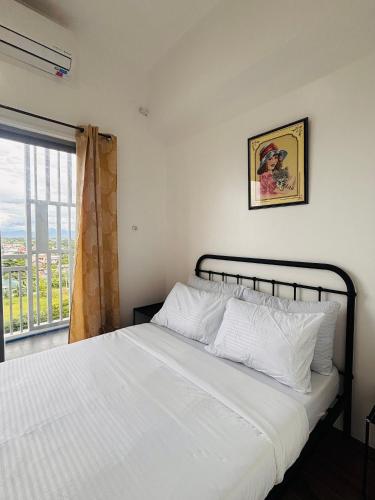 a bedroom with a white bed with a window at WV 29 Your Warm City Escape in Babuy