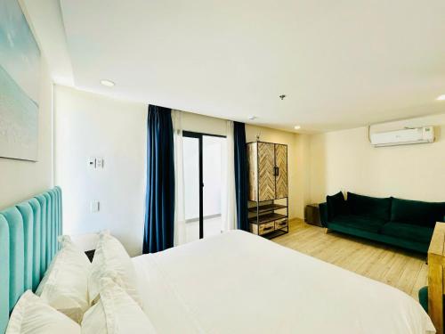 une chambre avec un grand lit blanc et un canapé dans l'établissement Oceanami Villa Resort Deluxe King - Đầy đủ tiện nghi - Hồ bơi 2000 m2 - Long Hải Beach, à Long Hải