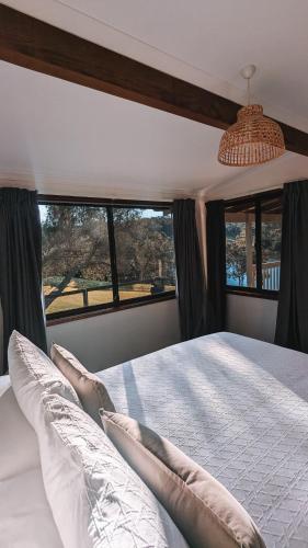 a bedroom with a bed with pillows and a window at Black Bream Point Cottages in Narooma