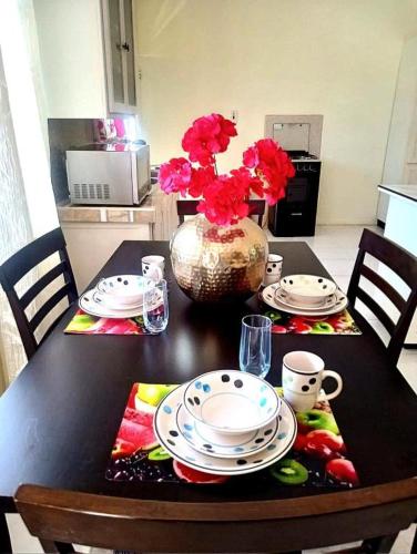 a table with two plates and a vase with flowers at Solace Stays in Arima