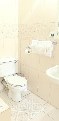 a white bathroom with a toilet and a sink at Solace Stays in Arima