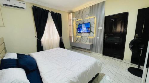 a bedroom with a bed and a tv on a wall at Liberty luxury home in Okunola