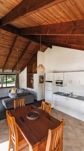 a kitchen and living room with a wooden table and chairs at Black Bream Point Cottages in Narooma