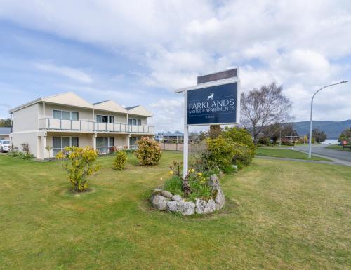a sign in front of a building with a house at Parklands Motel & Apartments Te Anau in Te Anau