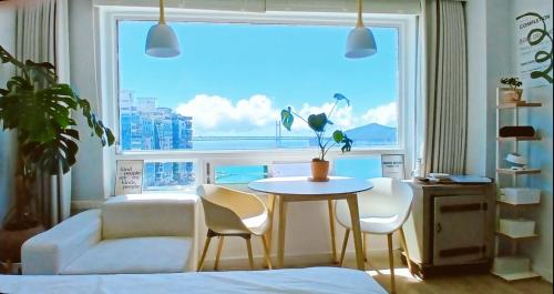 a living room with a table and chairs and a large window at Stay Gangali with view of Gwangan bridge in Busan