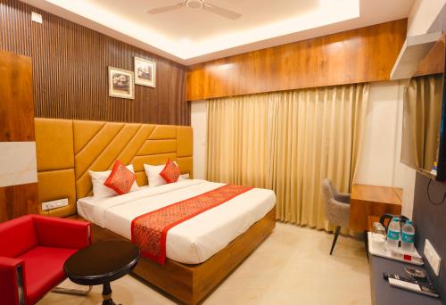 a hotel room with a bed and a red chair at Luxury stay by Pride Dabok - near Udaipur Airport in Udaipur
