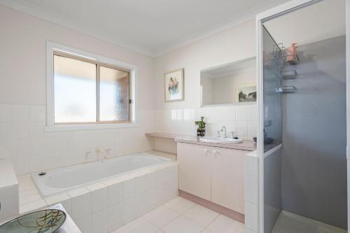 a white bathroom with a tub and a sink at Sienna Sunrise in Portarlington