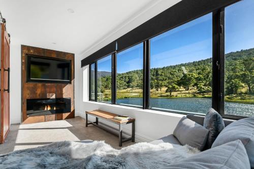 a living room with a couch and a large window at Elbert at Lake Crackenback Resort in Crackenback