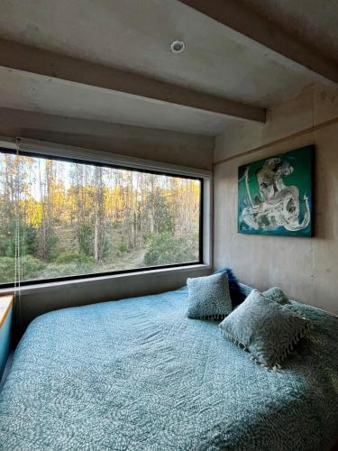 a bedroom with a bed and a large window at Tiny Houses del bosque in Pichilemu